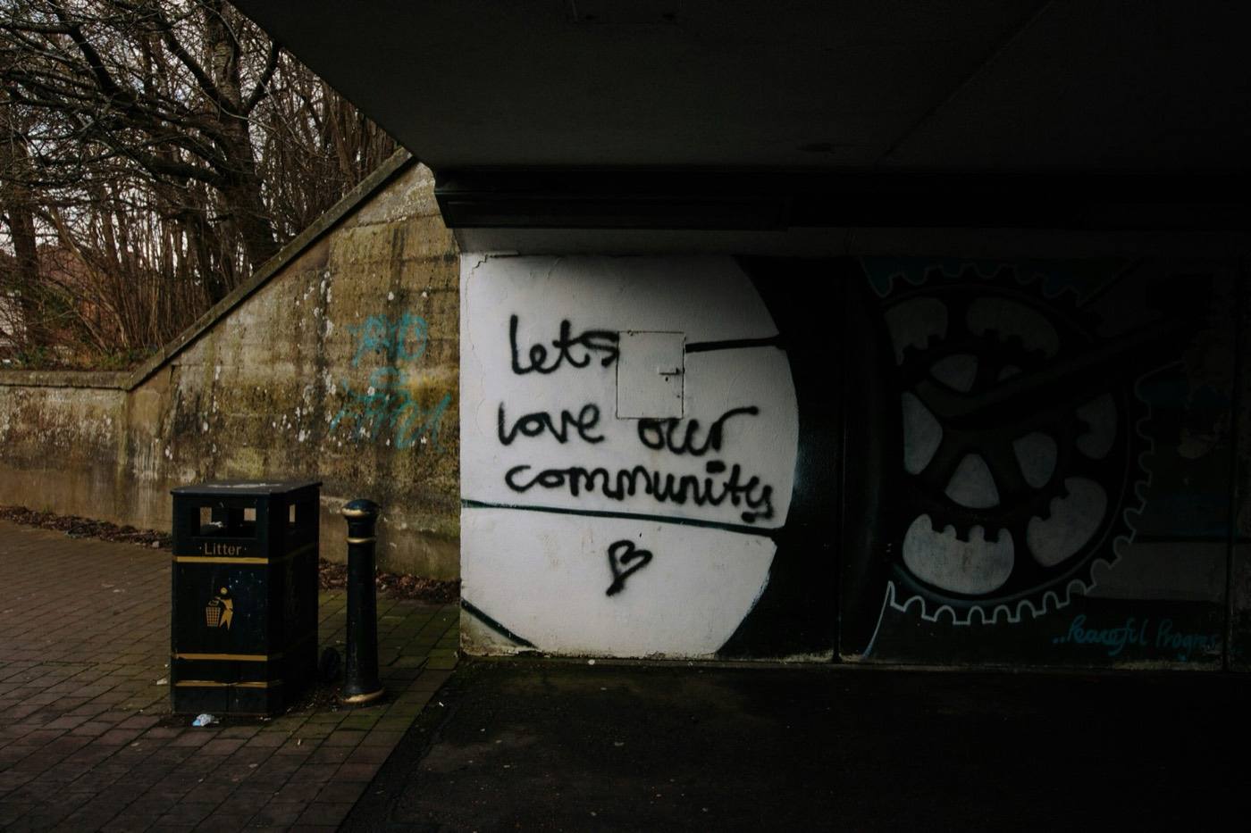 Graffiti med teksten Let's love our community under en bro